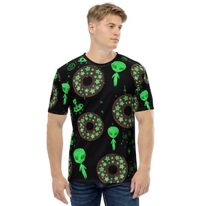 Puede incluir: Una camiseta negra con un patrón repetido de extraterrestres verdes, donuts con estrellas verdes y platillos voladores.