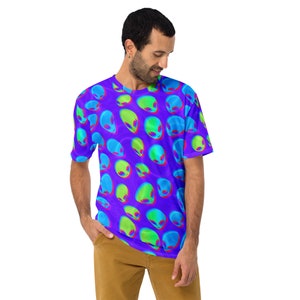 Puede incluir: Una camiseta morada con un patrón repetido de cabezas de extraterrestres verdes y azules. Las cabezas de extraterrestres están en estilo 3D y tienen un aspecto psicodélico.