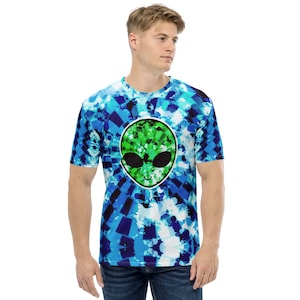 Puede incluir: Una camiseta azul y blanca de tie-dye con un gráfico de cara de extraterrestre verde. El extraterrestre tiene ojos negros y una pequeña sonrisa.