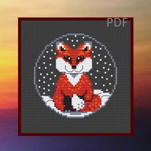 May include: Cross stitch pattern featuring a red fox sitting in a circle of white snowflakes on a gray background. The fox has a white chest and a white tip on its tail.