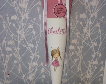 May include: A pink and white school cone with a pink ribbon and a white tag that says "mein erster Schultag" (my first day of school). The cone is decorated with a pink princess illustration and the name "Charlotte".