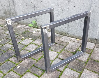 May include: Two metal table legs made of square steel tubing. The legs are welded together to form a rectangular frame. The legs are unfinished and have a raw metal finish.