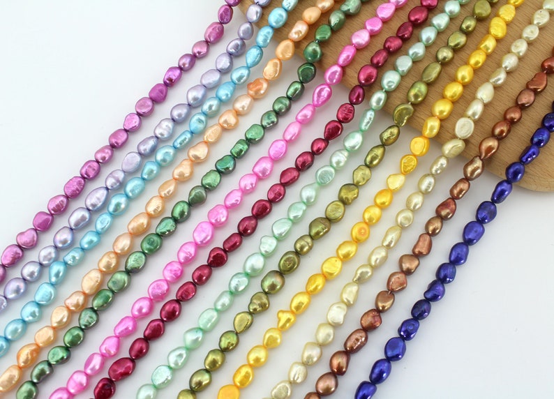 May include: A strand of iridescent baroque pearls in various colors, including blue, green, pink, and gold. The pearls are strung on a clear thread and are arranged in a line.