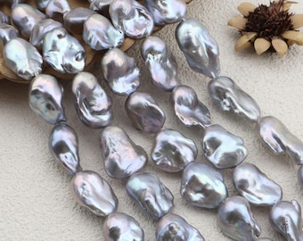 May include: Strands of iridescent, baroque-shaped pearls in shades of silver and grey. The pearls have a lustrous sheen and irregular shapes, suggesting a natural origin. The image shows multiple strands, ideal for jewellery making.