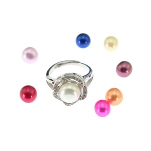 May include: A silver ring with a white pearl set in a flower design. The ring is surrounded by small colorful pearls in pink, red, blue, yellow, and brown.