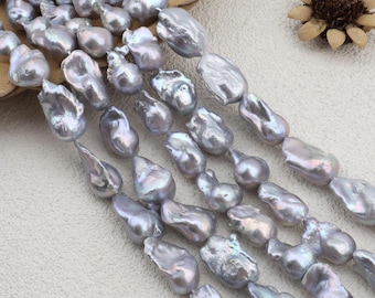 May include: Close-up of multiple strands of grey and silver baroque pearls. The pearls have an irregular, organic shape and a shimmering, iridescent surface. The image shows several strands, likely for jewellery making. The background is neutral, emphasising the pearls' beauty.
