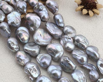 May include: Close-up of strands of large, grey baroque pearls. The pearls are irregularly shaped with a lustrous, iridescent sheen, reflecting colours of blue, green, and purple. The pearls are strung together, ready for jewellery making.