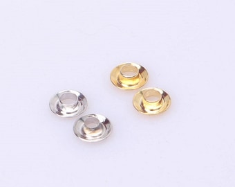 May include: Four metal eyelets, two gold and two silver, with a round shape and a hole in the center.