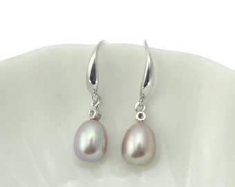May include: A pair of silver dangle earrings with a pearlescent drop. The pearls are a light lavender colour.