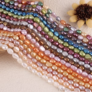 May include: A strand of iridescent freshwater pearls in various colors, including white, pink, peach, lavender, brown, green, and blue. The pearls are oval shaped and have a smooth, polished finish.