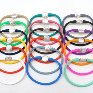 May include: A set of 16 colourful silicone bracelets with a pearl accent. Each bracelet is a different colour, including red, orange, yellow, green, blue, purple, pink, and brown.