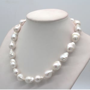 Op de afbeelding: Een witte barokparelsnoer met grote, onregelmatig gevormde parels. De ketting wordt getoond op een wit mannequin.