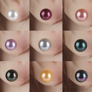 Könnte beinhalten: Neun unterschiedlich farbige Perlen, die jeweils am Ohr eines Modells gezeigt werden. Die Perlen sind weiß, rosa, lila, grau, schwarz, gold und schillernd.