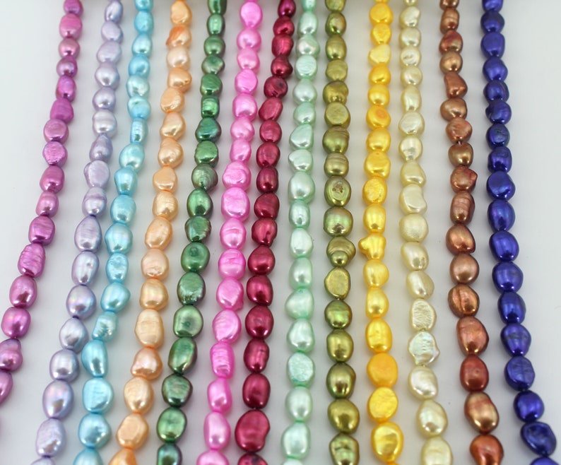 May include: A strand of 12 different colored freshwater pearls. The pearls are all irregular in shape and have a slightly iridescent finish. The colors include purple, blue, light blue, peach, green, pink, red, light green, gold, yellow, brown, and blue.