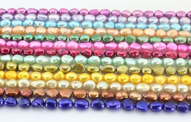 May include: A strand of iridescent baroque pearls in various colors, including pink, purple, green, yellow, and brown. The pearls are arranged in rows, with each row featuring a different color.