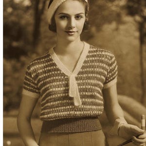 Puede incluir: Imagen sepia de una persona con un top de punto con rayas horizontales en tonos marrón y blanco. El top tiene mangas cortas y cuello en V con detalle de lazo. La persona también lleva una boina a juego.