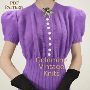 Puede incluir: Un cárdigan de punto morado con mangas cortas abullonadas y botones blancos. El texto "PDF PATTERN" está en la esquina superior izquierda y "Goldmine Vintage Knits" en el centro inferior. Un broche decorativo está prendido cerca del escote.