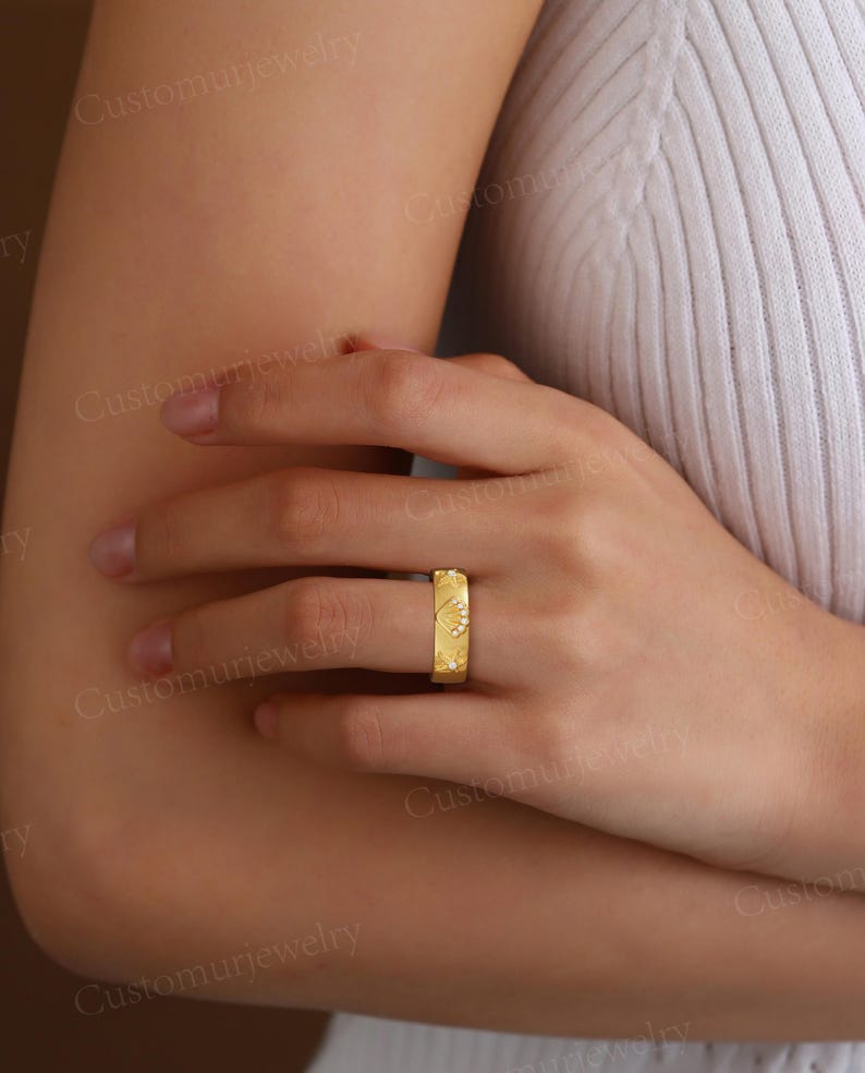 A close-up of a person's hand wearing a gold ring on the ring finger.