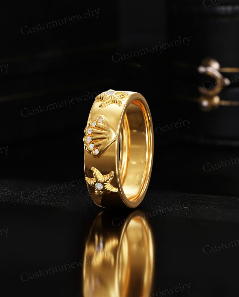 A gold ring with a shell and starfish design is displayed against a black background.