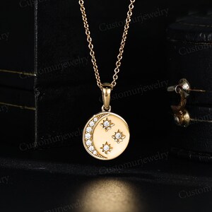 A gold necklace with a circular pendant featuring a crescent moon design and three small stars.