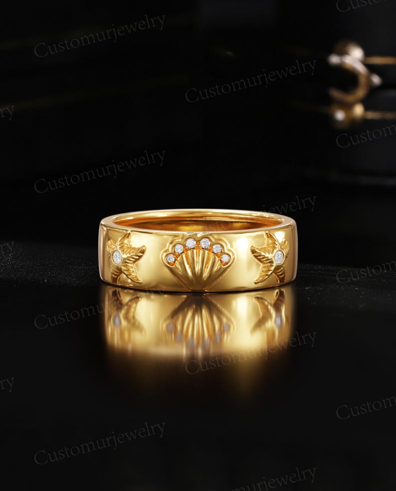 A gold ring with a shell design and small diamonds is displayed against a black background.