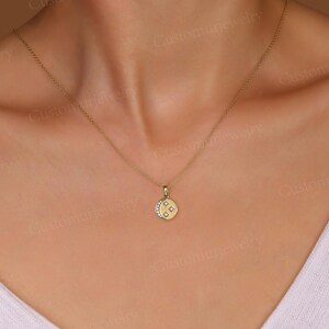 A close-up view of a woman's neck and chest area wearing a gold necklace with a small pendant.