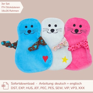May include: A set of three plush seal-shaped embroidery designs in blue, white, and pink. Each features a stitched face, a knotted fabric bow, and a small embroidered shape: a red heart, a yellow star, and a floral pattern. Text reads 3er Set.