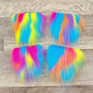 May include: Four colorful faux fur patches in shades of blue, pink, yellow, and orange. The patches are arranged in a square pattern on a wood background.
