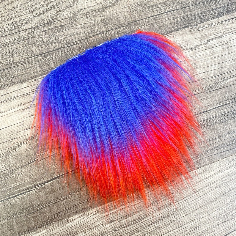 Op de afbeelding: Een blauwe en rode ombre-vachtstrook. De vacht is lang en pluche, met een gradi&euml;nt van blauw naar rood.