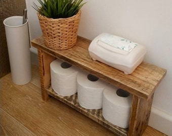 Puede incluir: Estantería rústica de baño de madera con tres rollos de papel higiénico blanco, una cesta tejida con hierba verde y un dispensador de toallitas blancas. Para el almacenamiento del baño.