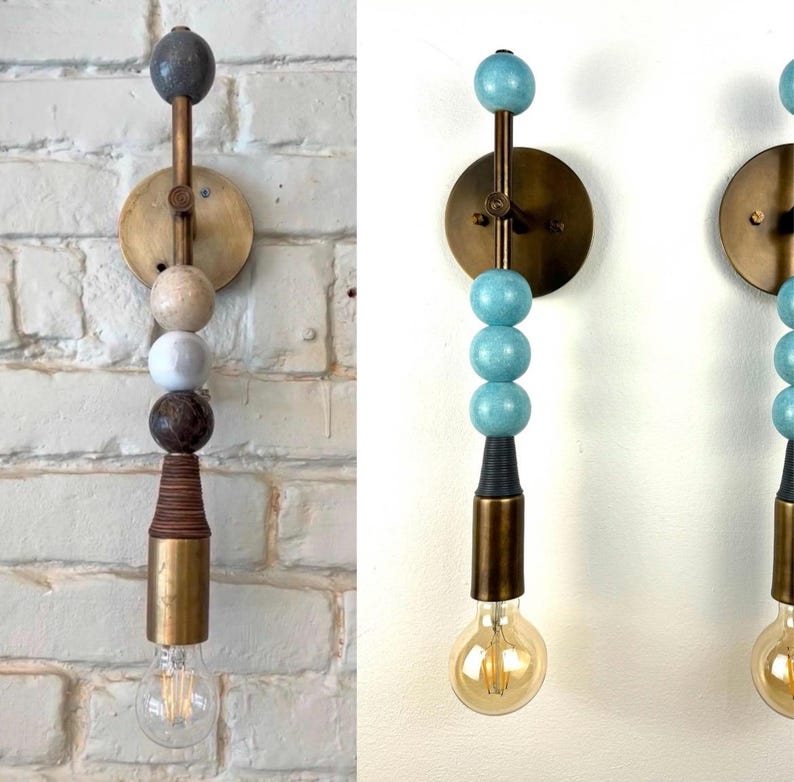 Peut inclure: Une applique murale compos&eacute;e d'une tige verticale en laiton orn&eacute;e de perles sph&eacute;riques empil&eacute;es aux couleurs et textures vari&eacute;es, incluant des tons bleus, beiges et bruns, termin&eacute;e par une douille cylindrique en laiton avec une ampoule claire.