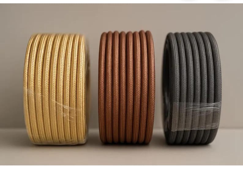 Peut inclure: Trois bobines de fil &eacute;lectrique d&eacute;coratif en or, cuivre et gris. Les fils sont &eacute;troitement enroul&eacute;s et envelopp&eacute;s dans du plastique transparent. Les bobines sont dispos&eacute;es c&ocirc;te &agrave; c&ocirc;te sur un fond neutre. Les fils conviennent aux projets d'&eacute;clairage.