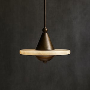 Könnte beinhalten: Eine moderne Pendelleuchte mit Bronze-Finish. Sie hat eine konische Oberseite, einen kreisförmigen Alabasterschirm und ein dekoratives Unterteil. Die Leuchte hängt an einer schlanken Stange.