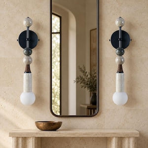 Peut inclure: Deux appliques murales composées d'un empilement vertical de sphères et de cylindres aux textures et couleurs variées, incluant le vert foncé, le beige et le brun, terminées par un globe en verre dépoli blanc à la base.