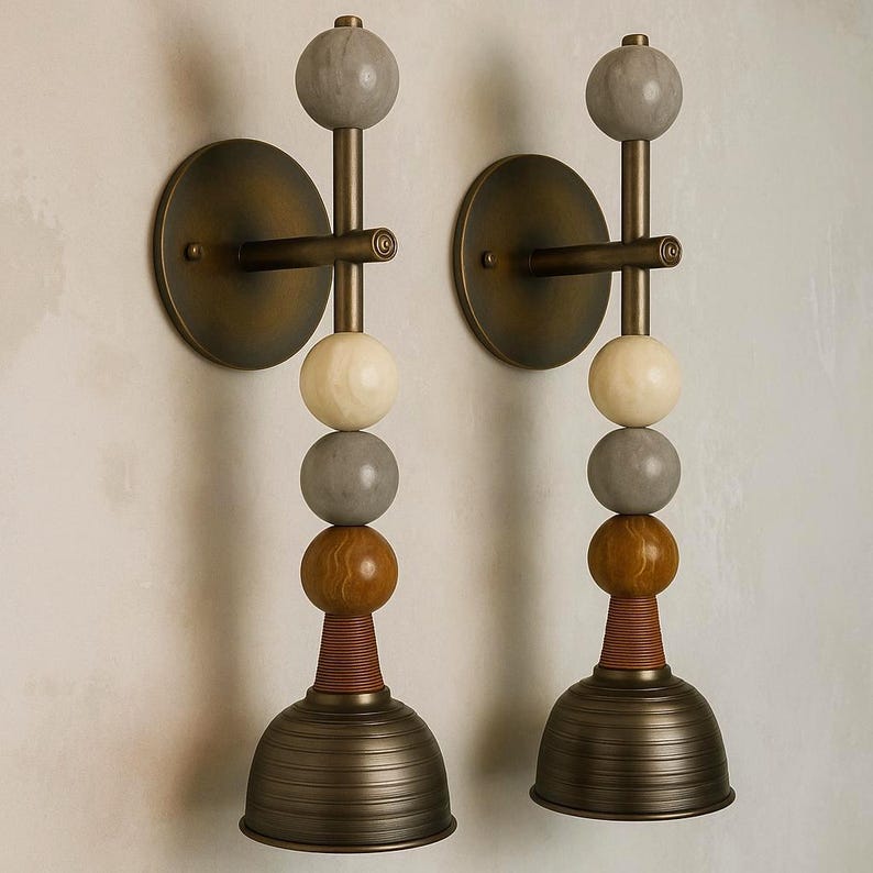 Peut inclure: Une paire d'appliques murales compos&eacute;es d'une tige m&eacute;tallique verticale fix&eacute;e &agrave; une plaque murale circulaire. Chaque luminaire est orn&eacute; d'une pile d'&eacute;l&eacute;ments sph&eacute;riques gris, cr&egrave;me et marron, termin&eacute;s par un abat-jour en m&eacute;tal nervur&eacute;.