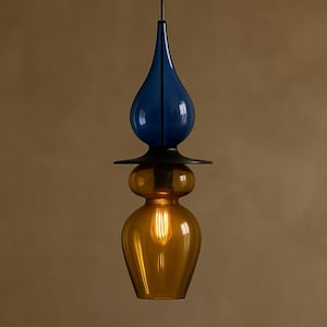 Peut inclure: Un luminaire suspendu moderne avec un design en couches. La partie sup&eacute;rieure est en forme de goutte d'eau bleu fonc&eacute;, suivie d'un disque noir et d'une base bulbeuse jaune dor&eacute;. L'ampoule est visible &agrave; l'int&eacute;rieur.