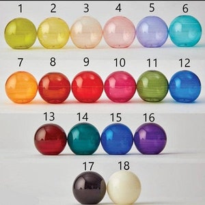 May include: A collection of eighteen colorful, spherical glass objects. The spheres are arranged in rows, showcasing a variety of transparent colors including green, yellow, pink, blue, and red. Each sphere is numbered from 1 to 18.