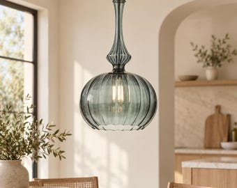 May include: A pendant light fixture featuring a translucent, smoke-gray glass shade with a vertical ribbed texture. The shade has a wide, rounded base that tapers into a slender, elongated neck, suspended by a thin metal cord from the ceiling.