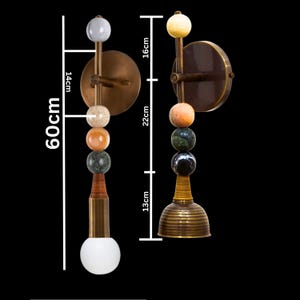 Peut inclure: Deux appliques murales avec des plaques arri&egrave;re circulaires en laiton et des tiges verticales orn&eacute;es de pierres sph&eacute;riques empil&eacute;es de diff&eacute;rentes couleurs. La hauteur totale est de 60cm, avec des segments de 14cm, 16cm, 22cm et 13cm. Une lampe a une ampoule globe blanche.