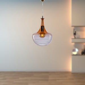 Puede incluir: Una lámpara colgante de vidrio transparente con la parte superior marrón y una bombilla de luz blanca cálida. La luz cuelga de un techo blanco.