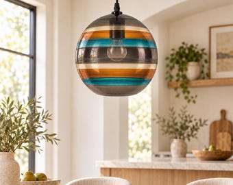 May include: A spherical glass pendant light fixture featuring horizontal bands of translucent amber, turquoise, and grey colors. The globe is suspended by a thin black cord and contains a single clear light bulb visible through the glass.