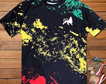 May include: Black t-shirt with a colorful paint splatter design in red, yellow, and green. A white lion logo is centered on the shirt.