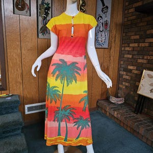 May include: A vintage, floor-length dress with a vibrant tropical design. The dress features a color gradient of yellow, orange, and red, with teal palm trees. It has short sleeves and a keyhole neckline, perfect for a retro summer look.