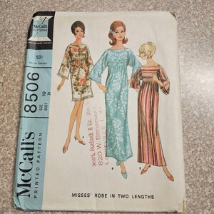May include: A vintage McCall's 8506 sewing pattern envelope for a robe in two lengths. The cover features illustrations of three figures wearing different versions of the robe: a short floral print, a long light blue floral, and a long striped design.