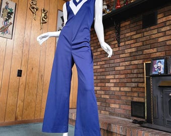 May include: A blue jumpsuit with a white V-neck and white trim on the sleeves. The jumpsuit has a wide leg.
