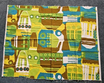 May include: A rectangular piece of fabric with a repeating abstract pattern in shades of brown, green, yellow, blue, and white. The design features geometric shapes and stylized forms. The fabric has a raw edge.