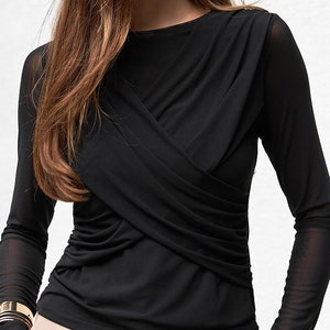 May include: A black long-sleeved shirt with a criss-cross design in the front. The shirt is made of a sheer fabric and has a relaxed fit.