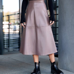 Pu&ograve; includere: Una gonna midi in similpelle color malva con una silhouette svasata. La gonna ha un'alta vita e un design semplice.