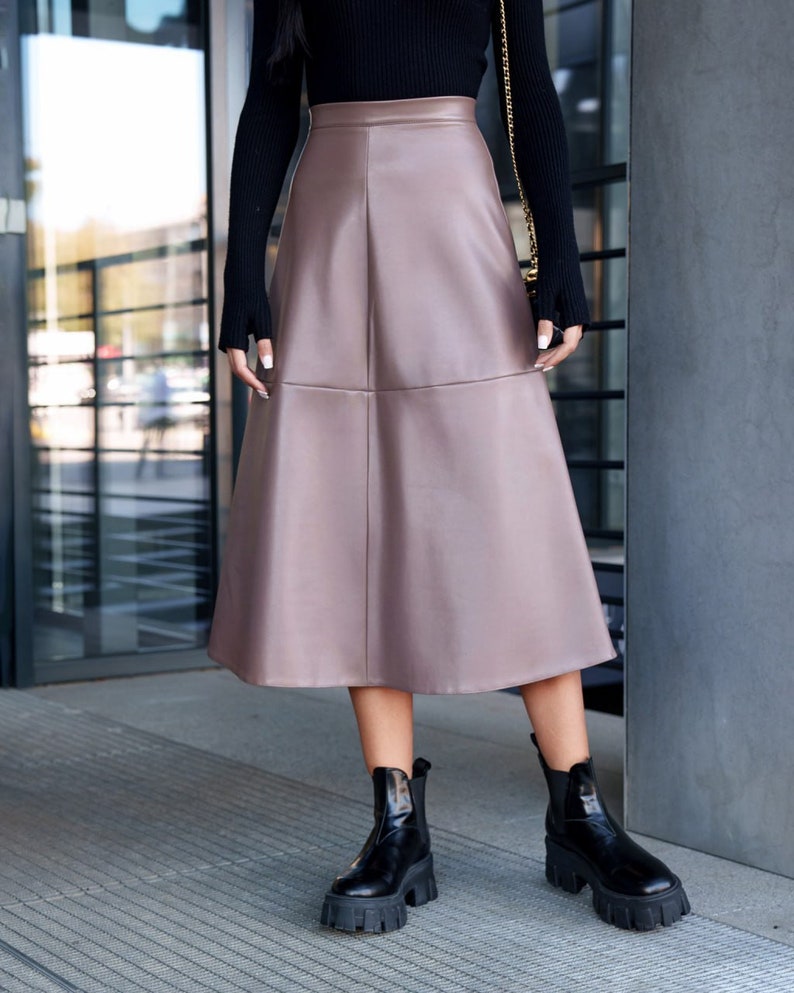 Pu&ograve; includere: Una gonna midi in similpelle color malva con una silhouette svasata. La gonna ha un'alta vita e un design semplice.