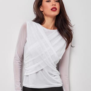 May include: A white long-sleeved mesh top with a criss-cross design in the front. The top is semi-sheer and has a relaxed fit.